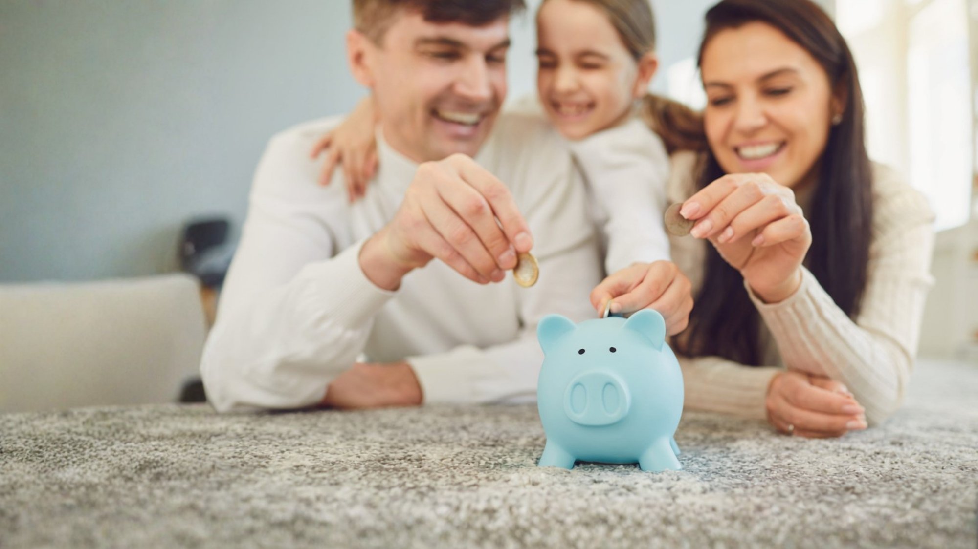 young family putting coins in piggy bank