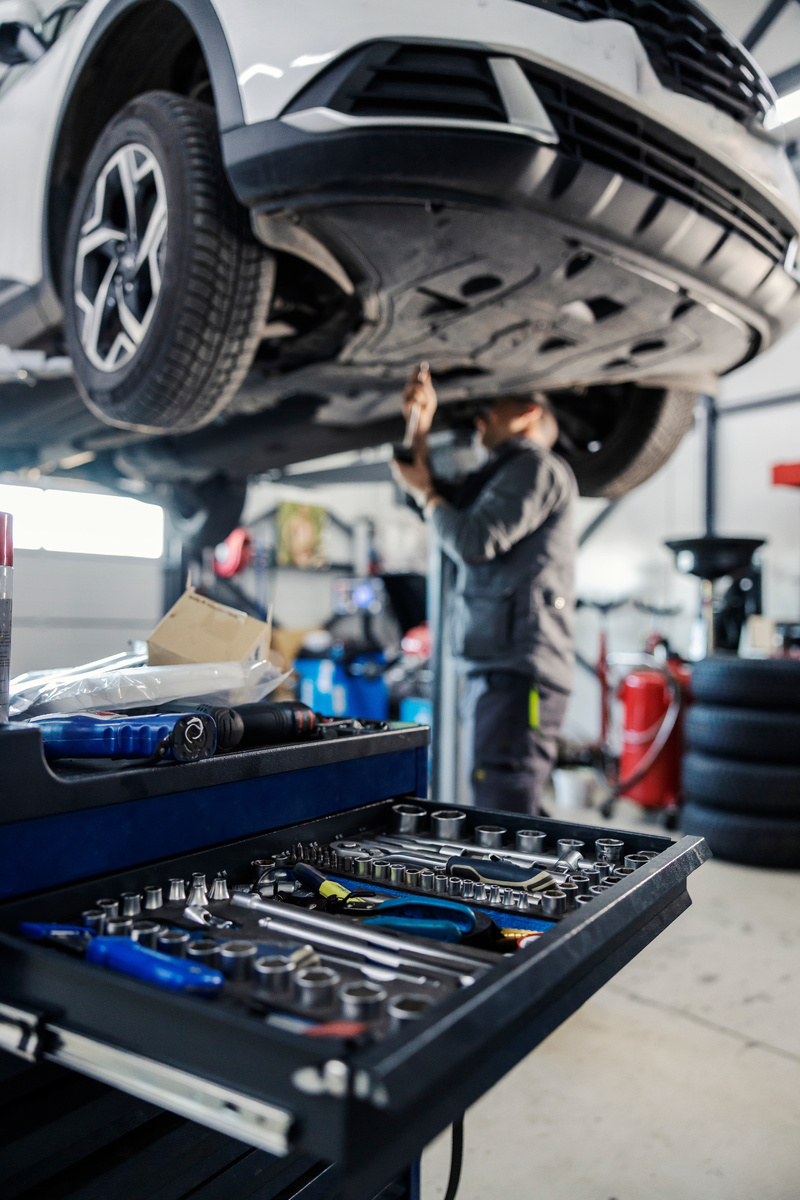 mechanic working on under carriage of a car