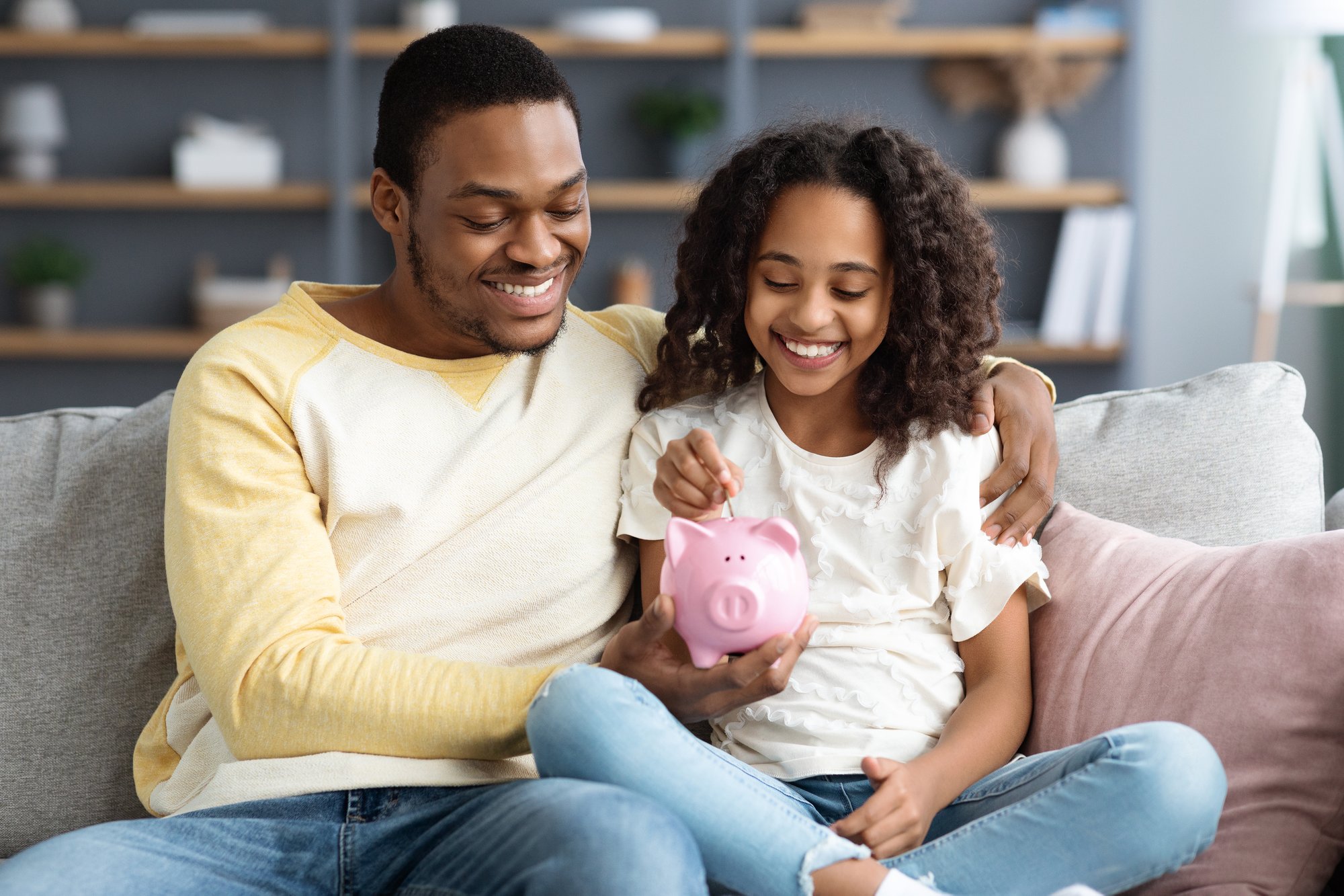 black-girl-and-father-putting-coin-into-piggy-bank-2022-12-16-06-33-48-utc